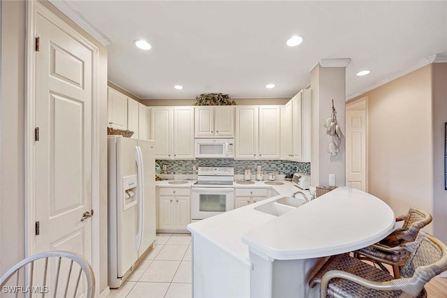 kitchen with sink, white appliances, a breakfast bar area, light tile patterned floors, and kitchen peninsula