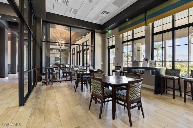 dining room with a towering ceiling, light hardwood / wood-style floors, and a chandelier