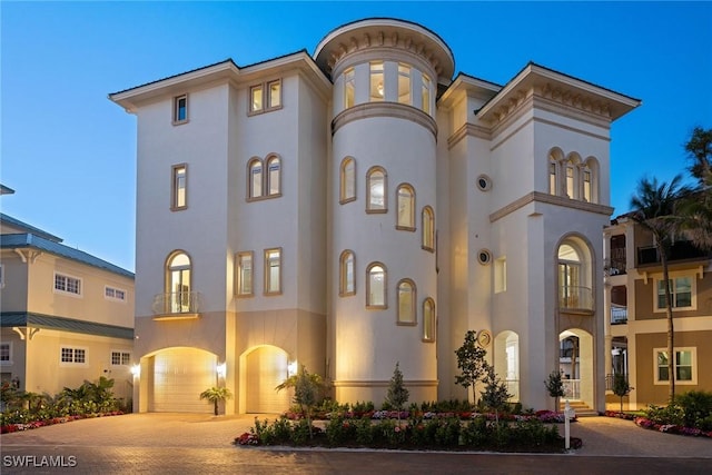 mediterranean / spanish house featuring stucco siding, an attached garage, and decorative driveway