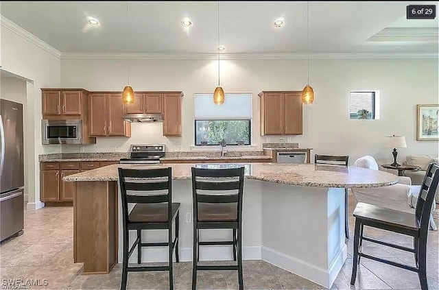 kitchen with stainless steel appliances, a center island, ornamental molding, light stone countertops, and a kitchen breakfast bar