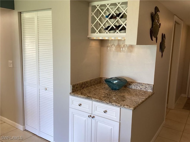 kitchen featuring white cabinetry, light stone countertops, and light tile patterned floors