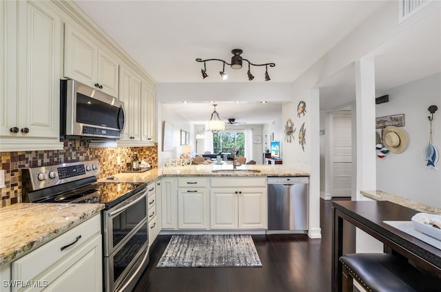 kitchen with sink, decorative backsplash, hanging light fixtures, kitchen peninsula, and stainless steel appliances