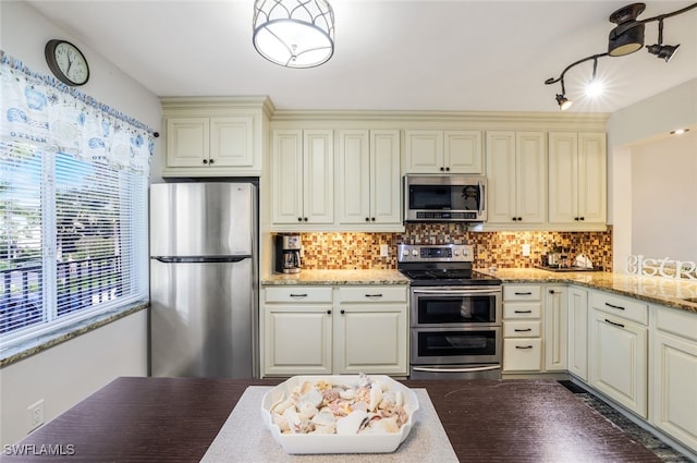 kitchen featuring tasteful backsplash, dark hardwood / wood-style floors, stainless steel appliances, light stone countertops, and cream cabinets