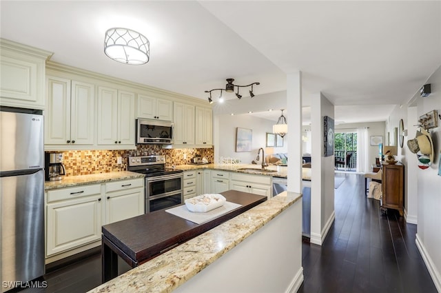 kitchen with tasteful backsplash, light stone countertops, appliances with stainless steel finishes, and sink