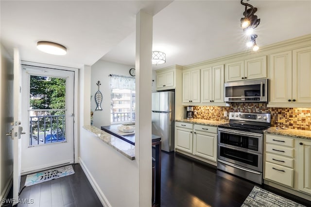 kitchen featuring tasteful backsplash, light stone countertops, stainless steel appliances, and cream cabinetry