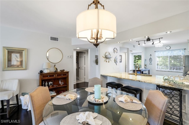 dining area featuring sink, hardwood / wood-style floors, and a notable chandelier