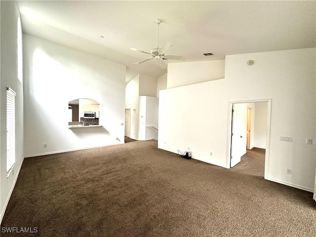 unfurnished living room with ceiling fan, high vaulted ceiling, and dark carpet