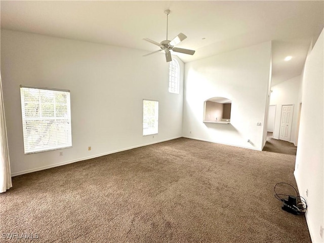 unfurnished living room featuring ceiling fan, high vaulted ceiling, and dark colored carpet