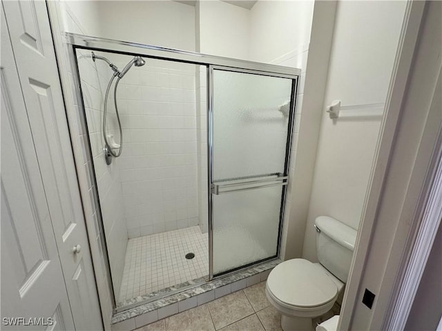 bathroom with an enclosed shower, tile patterned floors, and toilet