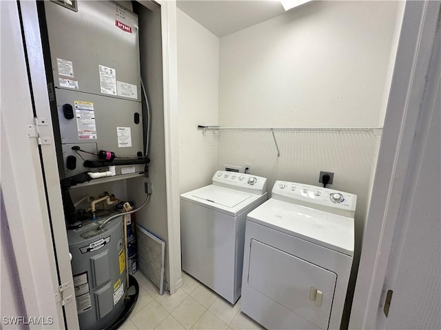 laundry room featuring electric water heater, independent washer and dryer, and light tile patterned flooring