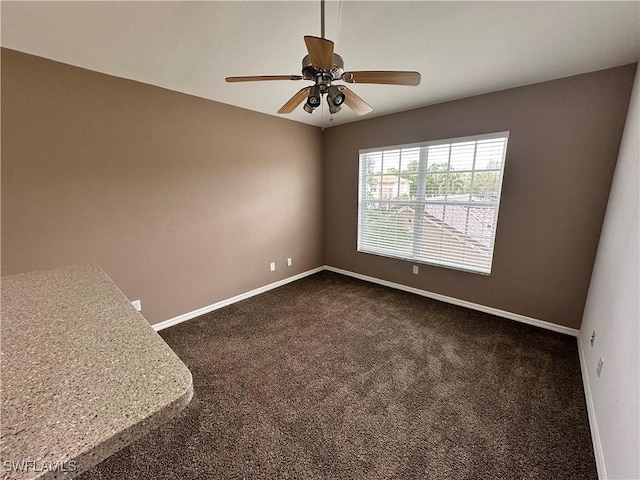 empty room with ceiling fan and dark carpet