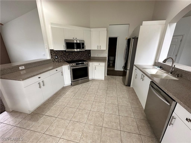 kitchen featuring light tile patterned flooring, appliances with stainless steel finishes, sink, white cabinets, and backsplash