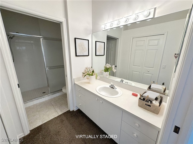 bathroom featuring tile patterned floors, toilet, a shower with door, and vanity