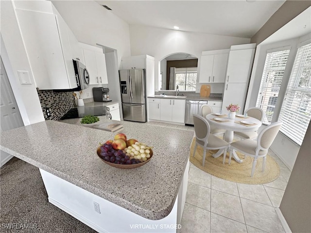 kitchen featuring appliances with stainless steel finishes, sink, lofted ceiling, white cabinets, and tasteful backsplash