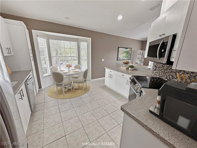 kitchen featuring white cabinetry, stainless steel appliances, light tile patterned floors, and decorative backsplash