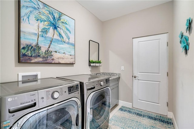 clothes washing area with separate washer and dryer and cabinets