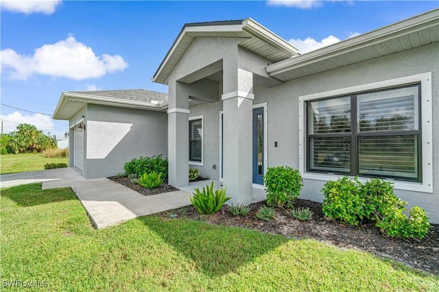 view of exterior entry featuring a garage and a yard