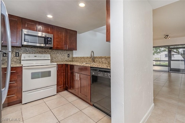 kitchen with appliances with stainless steel finishes, sink, backsplash, light tile patterned floors, and light stone counters