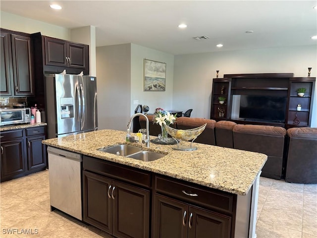 kitchen with a kitchen island with sink, sink, dark brown cabinetry, and appliances with stainless steel finishes