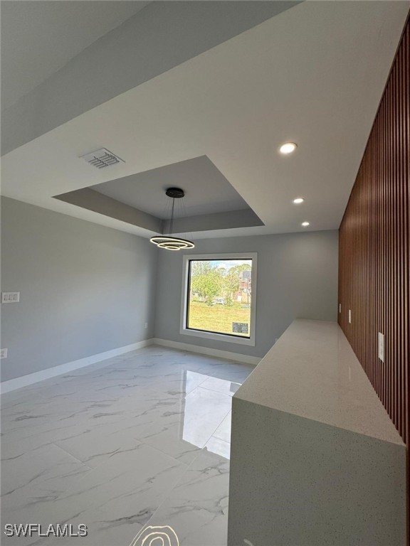 interior space with a raised ceiling and wooden walls