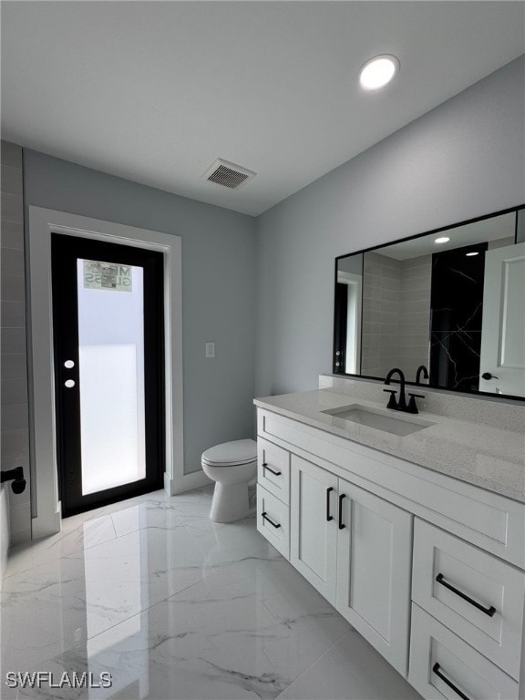 bathroom featuring vanity, walk in shower, and toilet