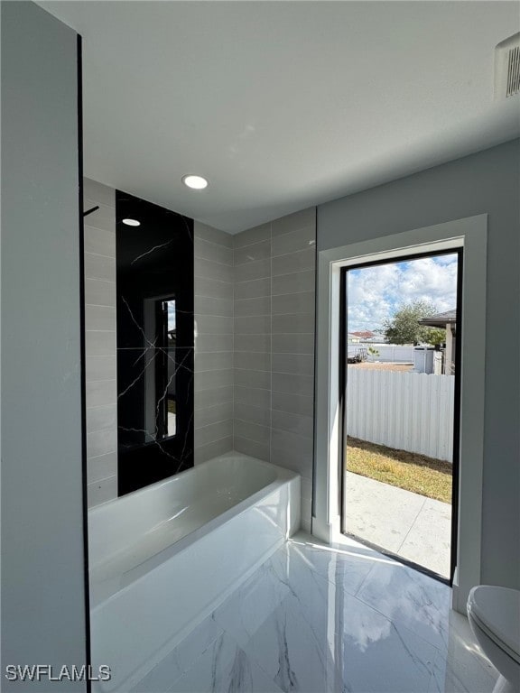 bathroom featuring tiled shower / bath and toilet