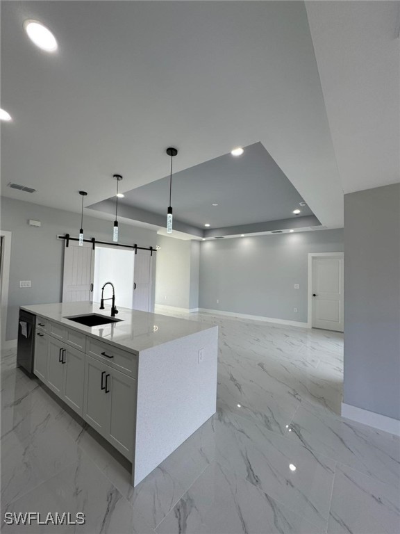 kitchen with sink, white cabinets, hanging light fixtures, a kitchen island with sink, and a barn door