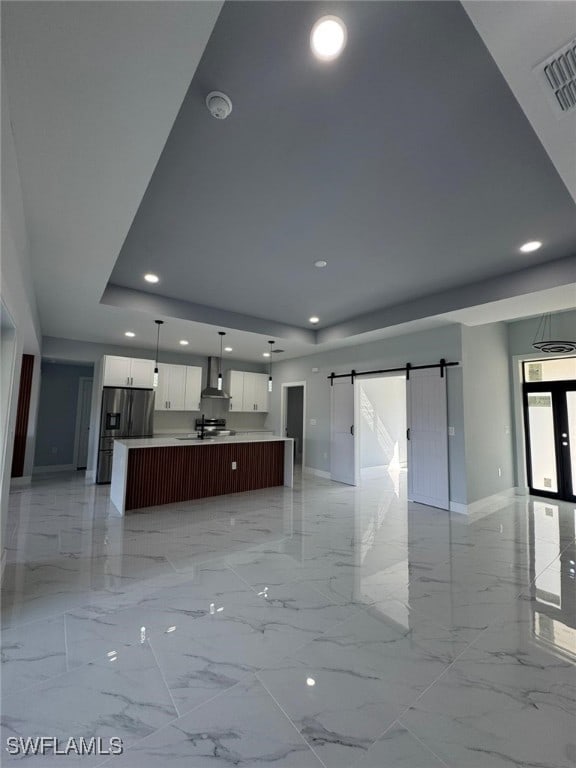 kitchen featuring white cabinets, hanging light fixtures, a large island, stainless steel refrigerator with ice dispenser, and wall chimney exhaust hood