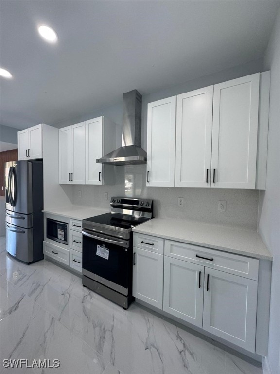 kitchen with tasteful backsplash, appliances with stainless steel finishes, white cabinets, and wall chimney exhaust hood