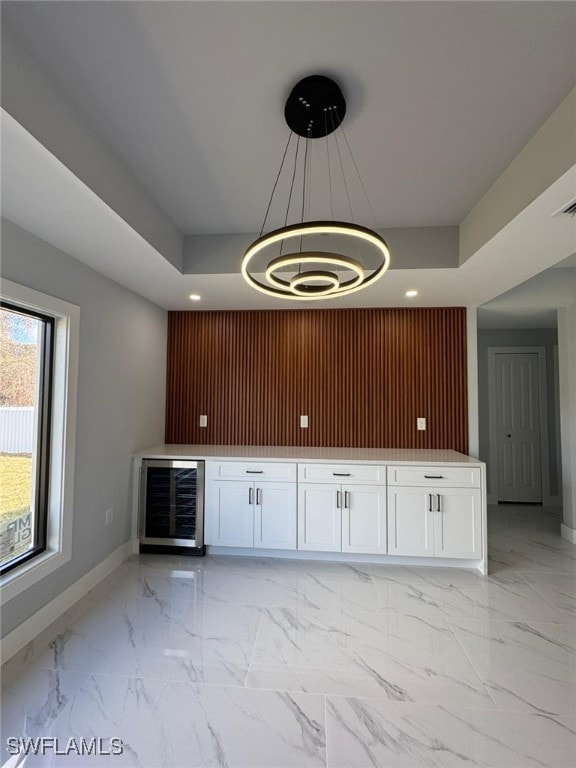 bar featuring decorative light fixtures, beverage cooler, a raised ceiling, and white cabinets