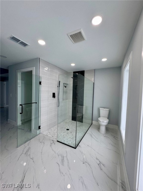 bathroom featuring toilet and a shower with shower door