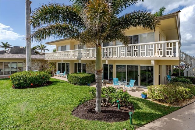 back of house featuring a yard, a patio area, and a balcony