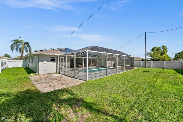 back of property featuring a patio, glass enclosure, a lawn, and a fenced in pool