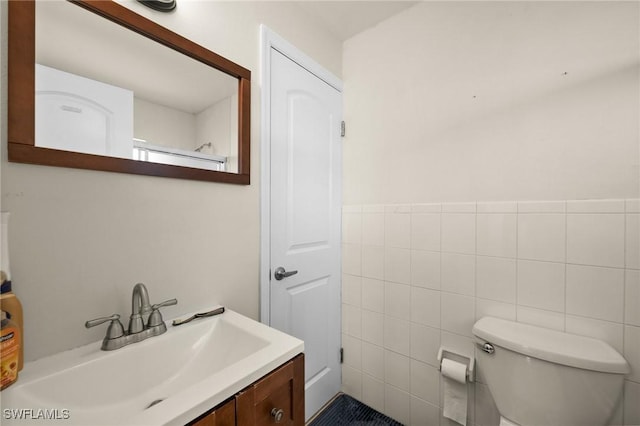 bathroom featuring vanity, tile walls, and toilet