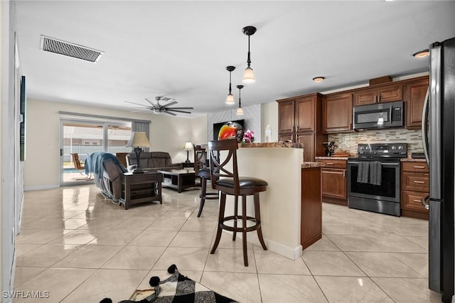 kitchen with appliances with stainless steel finishes, tasteful backsplash, light tile patterned flooring, and light stone counters