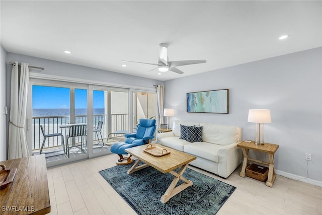 living room featuring light hardwood / wood-style flooring, ceiling fan, and a water view