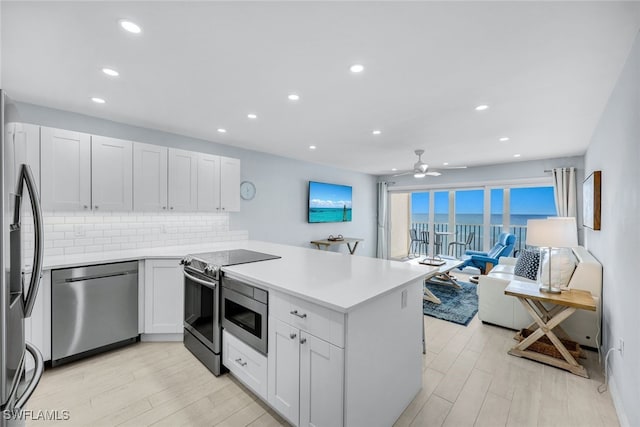 kitchen with white cabinetry, appliances with stainless steel finishes, kitchen peninsula, and tasteful backsplash