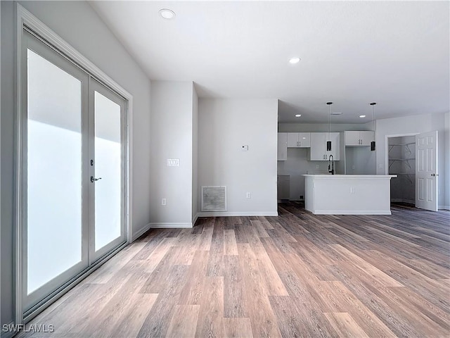 unfurnished living room featuring french doors, sink, and hardwood / wood-style floors