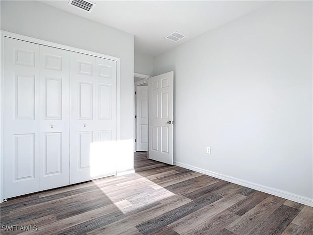 unfurnished bedroom featuring dark hardwood / wood-style flooring and a closet