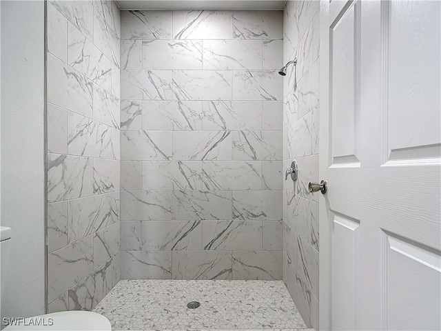 bathroom featuring toilet and a tile shower