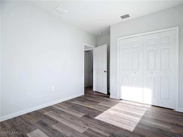 unfurnished bedroom with dark hardwood / wood-style flooring and a closet