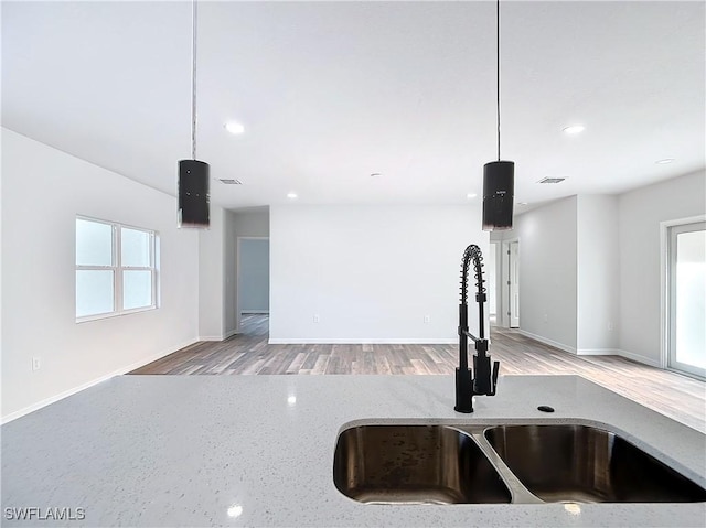 room details featuring hardwood / wood-style floors, light stone countertops, sink, and hanging light fixtures