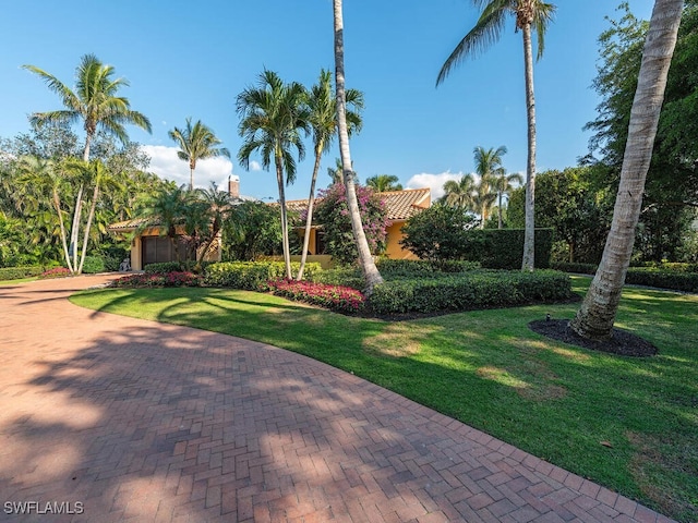 view of property's community with a garage, a yard, and decorative driveway