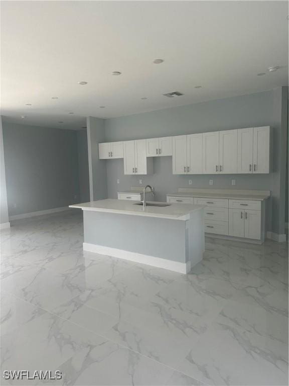 kitchen featuring white cabinetry, sink, and a kitchen island with sink