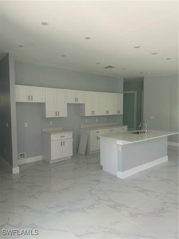 kitchen with sink, white cabinets, and a center island with sink