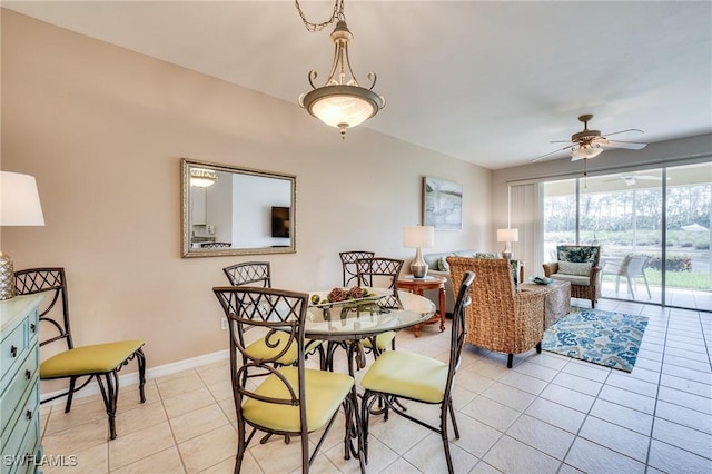 dining space featuring a ceiling fan, baseboards, and light tile patterned floors