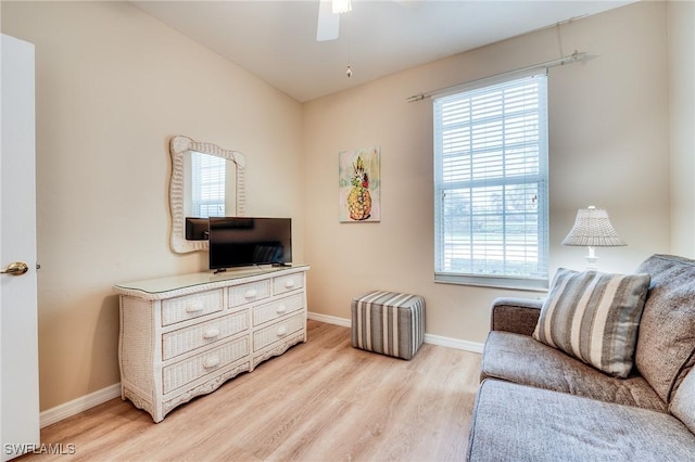 living area with baseboards, ceiling fan, light wood-type flooring, and a healthy amount of sunlight