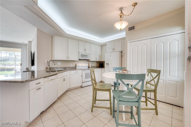 kitchen featuring light tile patterned floors, white appliances, a sink, visible vents, and a tray ceiling