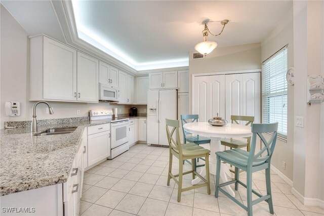 kitchen with white appliances, visible vents, light stone counters, and a sink