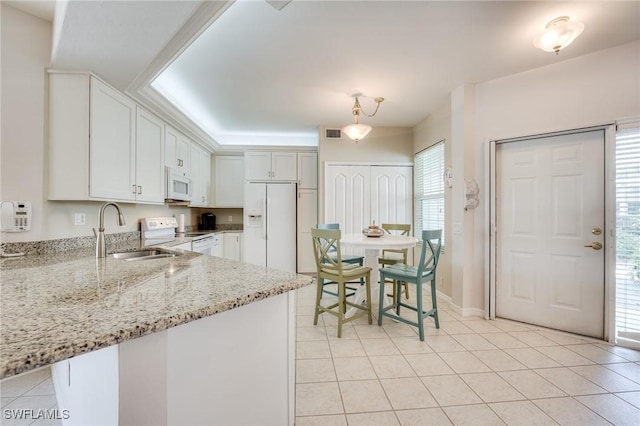 kitchen featuring light tile patterned floors, white appliances, a sink, visible vents, and light stone countertops